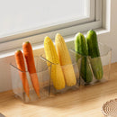 A Lovely Home Icon 1PCS Refrigerator Side Door Storage Box is placed on a wooden surface by a window, neatly organizing fresh vegetables—two carrots, two ears of corn, and two cucumbers—as sunlight streams across the scene.