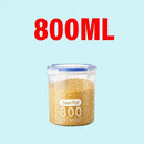 A clear Plastic Sealed Tank from Lovely Home Icon, labeled as a Large Capacity Crisper Kitchen Organize Grain Storage Box with Scale, is filled with yellow grains and features ‘800ML’ in large red text above it on a light blue background.