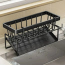 The Lovely Home Icon Sponge Draining Rack is a sleek black metal kitchen organizer featuring a rectangular basket and a waterproof drip tray positioned beneath it. Designed to rest on the edge of your sink, this versatile caddy efficiently holds dishcloths and dishwashing liquid, keeping water contained on the tray even when droplets collect on the countertop. Perfect for multiple uses, it ensures your kitchen essentials remain tidy and easily accessible.