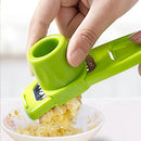 A hand uses the Lovely Home Icon 1PCS Garlic Crusher Press Multi-Functional Manual Ginger Garlic Grinding Grater Cutter to crush garlic into a small floral-patterned bowl.