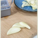 Three peeled garlic cloves rest on a wooden cutting board, with chopped garlic pieces on a blue patterned plate in the background, alongside the Lovely Home Icon Manual Pressing Garlic Grinding Grater Cutter Cooking Tool—a versatile, eco-friendly stainless steel kitchen accessory.