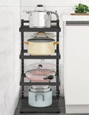 A black Lovely Home Icon Kitchen Sink Storage Rack, designed for easy assembly, neatly holds four pots of various colors and sizes on its multi-layer shelves, positioned beside a white counter with a chopping board and fresh herbs.