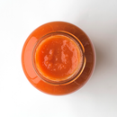 A top-down view of an open glass jar filled with smooth, bright orange-red Taycte Famiglia Crispino Classic Pasta Sauce Starter — Traditional Italian Base by Taycte, set against a plain white background.