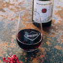 A personalized Stemless Wine Glasses - Set of 4: The Classic etched with the name ANDERSON in a geometric shape, resting beside a wine bottle and a cluster of red berries.