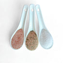 The Saltopia SALT SNOBS Gift Set by SALTOPIA Infused Sea Salts features three ceramic spoons holding Pink Himalayan, mixed herb, and gourmet sea salts, beautifully arranged on a white background.