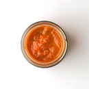 Top view of a glass jar filled with vibrant orange-red Famiglia Crispino Tropea Red Onion Pasta Sauce — IGP Certified Italian by Taycte, enriched with the sweetness of Cipolla Rossa di Tropea IGP, placed on a white background.
