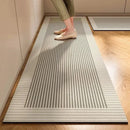 A person stands on the Lovely Home Icon New 1 pc Japanese style soft kitchen diatomite mud floor mat, a rectangular, striped rug in beige, gray, and cream tones. The super anti-slip and super absorbent carpet is placed on a wooden floor near light-colored cabinets; only the lower legs and feet are visible.