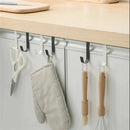 Five hooks from the Lovely Home Icon Multi-Purpose Hooks Kitchen Cabinet Door Back Hook Hanging Rack are installed under a light wood kitchen counter, holding scissors, an oven mitt, a brush, a whisk, and a spatula. This space-saving hanger features alternating black and white stainless steel hooks for stylish storage.