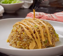 A mound of fried rice with vegetables and egg is served on a white plate, topped with Terrapin Ridge Farms Bang Bang Squeeze sauce drizzled in lines from a squeeze bottle.