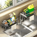 Two Lovely Home Icon Multifunctional Sponge Draining Racks—designed for holding sponges, dish soap, and kitchen towels—are installed at each sink. Each organizer provides dedicated space for cleaning supplies and includes a bar for hanging hand towels. A window above the sinks allows natural light to brighten the area.
