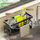 The Lovely Home Icon Sponge Draining Rack – Dishcloth & Dishwashing Liquid Storage, Kitchen Organizer, features durable black metal and plastic construction and holds sponges, brushes, detergent, and a checkered towel. Its waterproof design includes clearly labeled sections for each item and a practical drain tray underneath. Positioned by the faucet and window, this organizer is ideal for keeping your kitchen tidy and efficient.