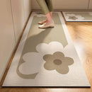 A person stands on the Lovely Home Icon New 1 pc Japanese style soft kitchen diatomite mud floor mat, a beige, super anti-slip and super absorbent runner featuring abstract floral patterns, complementing the wooden hallway flooring and light-colored walls with a touch of modern elegance.