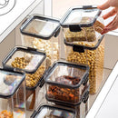 A hand lifts the lid of a Lovely Home Icon 1-4PCS Sealed Jar Kitchen Organizer Grain Storage Box, filled with spices and surrounded by similar large-capacity sealed containers holding nuts, beans, and dried foods—all neatly arranged on white shelves.