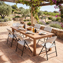 Enjoy outdoor dining with the DirectDeals Foldable Plastic Dining Chairs Set of 6 with Ergonomic Backrest, arranged around a wooden table set on a stone patio amid lush gardens and grapevines.
