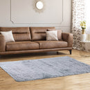 A modern living room features a Double Camping Chair with Carry Bag Cup Holders by DirectDeals, two beige pillows, a light gray shag rug, a round mirror, floral curtains, and a small table with a vase of yellow flowers.