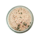 A glass jar of SALTOPIA Infused Sea Salts’ Saltopia Ranch Seasoning Low Sodium: SHOOK UP, showing its light brown, granular blend with visible dried herbs and spices, viewed from above on a white background.