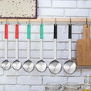 The Amazon 6 Pc Portion Control Serving Spoon Set features stainless steel spoons with red, green, and black handles, hanging on a wooden rack against a white brick wall—ideal for meal prep—shown beside cutting boards and jars.
