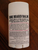 A white BBQ Boards® container labeled BBQ Board Balm® Care Pair Wax and Oil—a natural wood conditioner made with coconut oil, beeswax, and orange oil. Cutting board care instructions and website info are below the description.
