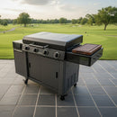 The BBQ Boards® 36" Blackstone Griddle Side Cutting Board is featured on a modern outdoor gas grill with three burners, set on a tiled patio overlooking a lush golf course and trees beneath a cloudy sky.