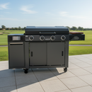 A BBQ Boards® 36" Blackstone Griddle Side Cutting Board sits on a large black outdoor gas grill with four knobs and side shelves, placed on a tiled patio overlooking a green lawn and golf course.