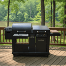 A BBQ Boards® Blackstone Pellet Grill Combo Front or Side Cutting Board by BBQ Boards® is set on a wooden deck with storage and side tables, overlooking a forest and lake—creating the ideal outdoor grill prep station for gatherings.