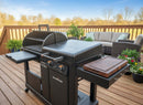 A BBQ Boards® Blackstone Pellet Grill Combo with a Front or Side Cutting Board by BBQ Boards® is displayed on a wooden deck, surrounded by patio furniture, potted plants, and trees beneath a clear blue sky.