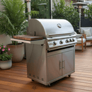 A large stainless steel gas grill with side shelves and multiple control knobs stands on a wooden deck, featuring the BBQ Boards® Blaze Grills LTE or LTE+ Side Cutting Board, surrounded by potted plants and outdoor furniture.
