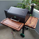A black GMG Daniel Boone Ledge pellet grill is outfitted with BBQ Boards® GMG Daniel Boone/Ledge Pair—front and side cutting boards. Ideal for outdoor cooking using versatile BBQ Boards® accessories.