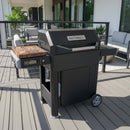 A BBQ Boards® Masterbuilt AutoIgnite Series 545 Side Cutting Board is displayed on a modern patio deck, accompanied by outdoor furniture and potted plants.