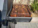 The BBQ Boards® Napoleon Freestyle Side Cutting Board by BBQ Boards® sits on the grill’s side board, ready for prep among patio plants and outdoor ambiance.