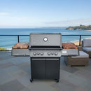 A Napoleon Prestige 500 gas grill is set on a patio overlooking the ocean, featuring BBQ Boards® Connected Side Cutting Boards (matching pair) by BBQ Boards®, with a scenic coastline and clear blue sky in the background.