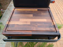The BBQ Boards® Traeger Ironwood Side Cutting Board by BBQ Boards® features a groove-edged, patchwork wood design with an engraved BBQ logo, making it a stylish and practical addition to your black grill prep workspace.