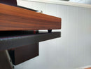 Close-up of a wooden desk with a textured black shelf, ideal for showcasing the BBQ Boards® Traeger Pro 34 Front Cutting Board against a white paneled wall in a well-lit room.