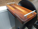 The BBQ Boards® Traeger Pro 34 Front & Pellet Bin Cutting Boards (Pair) feature varied wood tones, metal handles, a small engraved logo, and fit perfectly as front boards for the Traeger Pro 34 grill or smoker.