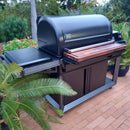 The BBQ Boards® Traeger Timberline XL Front Cutting Board by BBQ Boards® adds a spacious prep area to your grill setup, perfect for outdoor cooking on your patio surrounded by greenery.