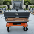 The BBQ Boards® Yoder Flat Top Front Cutting Board by BBQ Boards® is featured on a spacious patio with outdoor seating, lush plants, and a decorative waterfall in the background.