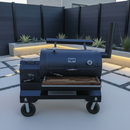 A black Yoder Smokers barbecue smoker with BBQ Boards® Yoder YS1500 Front & Pellet Bin Cutting Boards (Pair) sits on a modern patio with geometric pavers, minimal landscaping including agave plants, and a dark privacy fence.