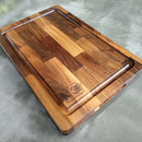 The BBQ Boards® Beastie BBQ Board® 18" x 12" Cutting Board features a juice groove and a BBQ-themed engraving in one corner, shown resting on a textured gray surface.