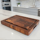 The Best BBQ Board® 16 x 12 Cutting Board by BBQ Boards® rests on a white kitchen countertop with modern cabinetry, a sink, and a built-in oven visible in the background.