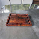 The Best BBQ Board® 16 x 12 Cutting Board by BBQ Boards® is a small, rectangular board with a grooved edge, rich dark wood grain, and a logo in one corner, displayed on a smooth gray countertop.