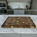 The BBQ Boards® Biggest BBQ Board® 36 x 24 Reversible Cutting Board with a checkered pattern sits on a marble kitchen island, with modern appliances and a sink visible in the background.