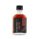 A clear glass bottle of Bourbon Barrel Foods Bourbon Barrel Aged Hot Sauce, with a black screw cap and label featuring the brand name, product name, and a red chili pepper illustration.