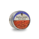 A round metal tin labeled Bourbon Barrel Foods Bourbon Smoked Chef's Blend, with a blue and beige design, contains a coarse, reddish bourbon smoked seasoning blend visible through the open lid.