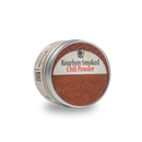 A round tin of Bourbon Barrel Foods Bourbon Smoked Chili Powder, featuring smoky reddish-brown seasoning made from New Mexico chili peppers, is displayed against a plain white background.