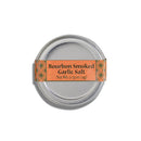 A small round tin of Bourbon Barrel Foods Bourbon Smoked Garlic Salt, 0.75 oz (21g), features an orange label and is shown from above on a white background.