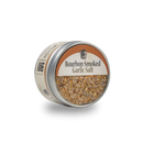 A round tin labeled "Bourbon Barrel Foods Bourbon Smoked Garlic Salt" holds a smoky, coarse seasoning blended with garlic. The Bourbon Barrel Foods container is displayed against a plain white background.