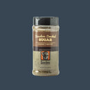A clear plastic shaker labeled "Bourbon Barrel Foods Bourbon Smoked Sugar," with brown and tan branding and a Louisville, Kentucky logo, sits against a plain dark background.