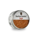 A round metal tin labeled "Bourbon Barrel Foods Bourbon Smoked Sugar" is filled with coarse smoked Demerara sugar and sits on a white background.