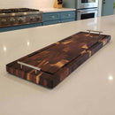 The Burly BBQ Board® 35 x 12 Cutting Board by BBQ Boards® with metal handles rests on a white kitchen countertop, doubling as a versatile tray. Blue cabinets and a stove add charm in the background.