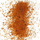 Chicken Fried BBQ Texas Sweet Grind by Chicken Fried BBQ features orange-brown coarse granules with dark specks, scattered on a white background—a perfect sweet heat BBQ rub for any competition.